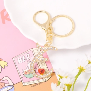 Detail of crystal letter E keychain with gold metal plating and small red heart charm