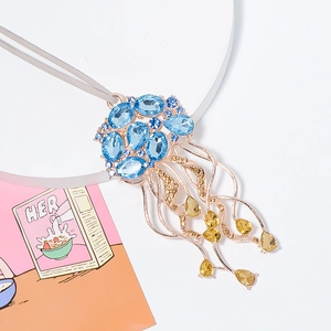 Pendentif méduse doré avec cristaux bleus et gouttes jaunes sur un cordon gris fin