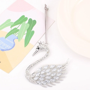 Macro detail of a silver swan pendant featuring crystal rhinestones and a grey cord strap