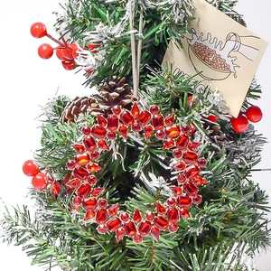 Macro view of gold metal wreath pendant with red gemstones on a festive tree branch