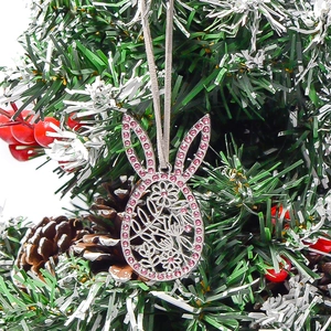 Detail eines silbernen Hasenohr-Ei-Anhängers mit rosa Strasssteinen am Weihnachtsbaum