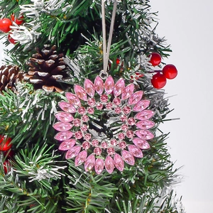 Pink rhinestone snowflake ornament with marquise crystals hanging on a Christmas tree branch