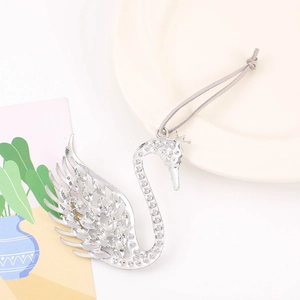 Elegant swan metal pendant with crown detail and intricate wing carvings on a white tray