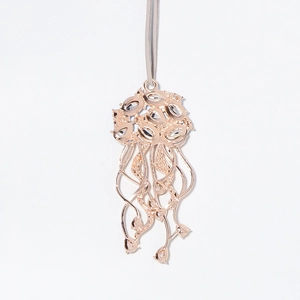 Détail du pendentif méduse en métal or rose évidé avec des strass brillants décoratifs