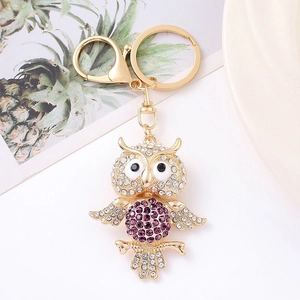 Detailed macro view of the golden owl keychain featuring purple and white rhinestones