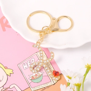 Close-up of golden letter K keychain with sparkling rhinestones and a red heart gemstone