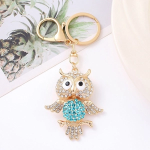 Close-up of owl keychain with sparkling blue rhinestones and golden metal finish