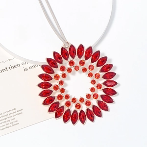 Macro shot of sunflower crystal pendant with red rhinestones and rose gold alloy plating