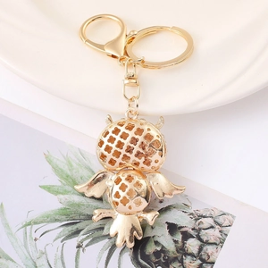 Golden owl keychain with clover cutout design on a clean lifestyle background