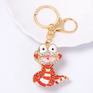 Detailed view of golden cartoon snake keychain with sparkling white and orange rhinestones