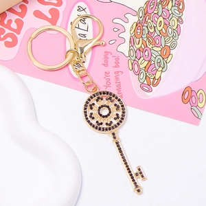 Detail of key-shaped gold-toned keychain with black rhinestones and lobster clasp