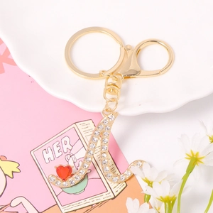 Detail of gold letter A keychain with sparkling crystals and a red heart pendant