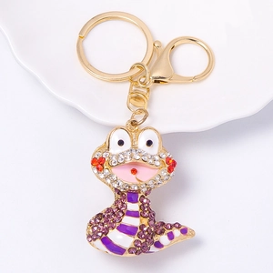 Detailed view of cartoon snake keychain with purple and white crystals on gold plating