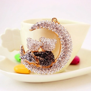 Sparkling moon and bear rhinestone keychain pendant displayed next to a coffee cup