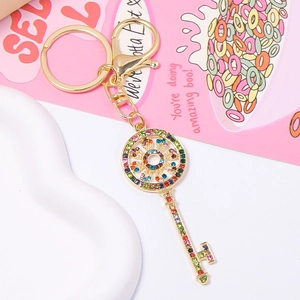 Detail of golden key keychain with colorful rhinestones and lobster clasp on pink background