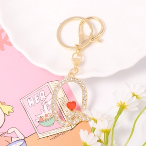 Detail view of crystal-encrusted gold letter Q keychain with small red heart charm