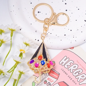 Gros plan d'un porte-clés parapluie doré orné de strass colorés et diamants brillants