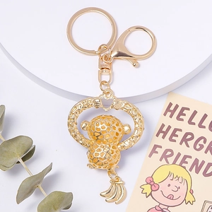 Golden hollow gorilla keychain with rhinestones, heart ring, and banana charm on a white stand