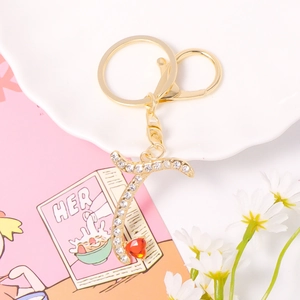 Detail of a gold-plated letter keychain with crystal rhinestones and a red heart charm