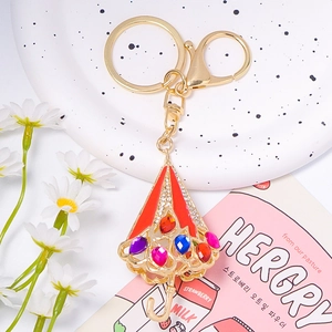Porte-clés parapluie doré avec strass colorés et fermoir homard sur plateau décoratif
