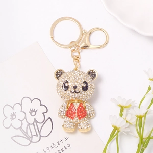 Sparkling rhinestone panda keychain in gold metal with red vest on a clean white background