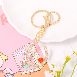 Detailed macro of crystal horseshoe keychain with red heart pendant on soft pink background