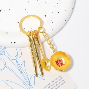 Detailed view of golden tableware keychain with chopsticks, spoon, and fortune bowl