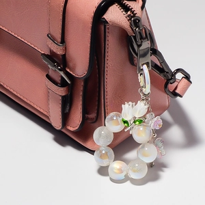 Détail du porte-clés tulipe avec perles irisées sur un sac en cuir rose
