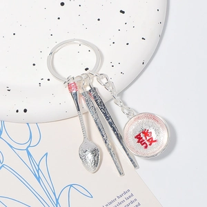 Detail showing silver tableware keychain with spoon, chopsticks and lucky tag