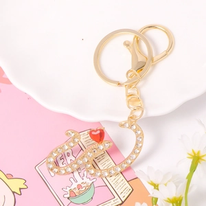 Detail of crystal letter S keychain with gold finish, clear rhinestones and red heart charm