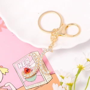 Detail of golden letter X keychain with crystals, red heart gem and moon charm