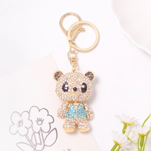 Close-up of sparkling rhinestone bear keychain with blue vest and gold-plated hardware