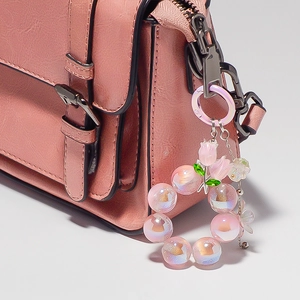 Gros plan du porte-clés tulipe rose sur sac en cuir avec breloque fleur en résine