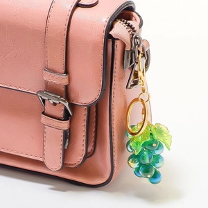 Gedetailleerde close-up van een groene en blauwe hars druif hanger aan een roze tas