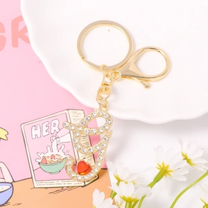 Macro detail of gold letter G keychain with sparkling rhinestones and a red heart gem