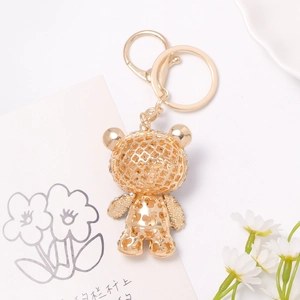Golden bear keychain with hollow floral patterns and sparkling rhinestones on white desk