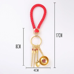 Detail of Chinese style keychain with golden mini bowl, spoon, chopsticks and red cord