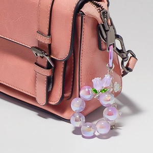 Vue détaillée d'un pendentif perlé tulipe violette sur un sac à main en cuir texturé rose