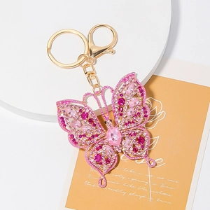 Detailed macro view of pink butterfly keychain with crystals on a decorative floral card