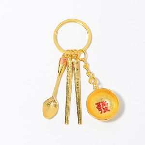 Golden tableware keychain set with mini spoon, bowl and chopsticks pendants on white background