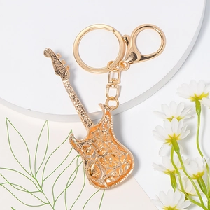 Golden electric guitar keychain with hollow floral pattern on a white pedestal display