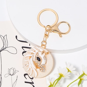 Detailed close-up of golden horse head keychain with white rhinestones and enamel finish