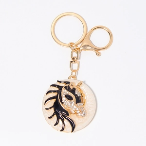Golden horse head keychain with sparkling rhinestones and marble pattern on white background