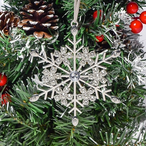 Silver snowflake Christmas ornament with sparkling rhinestones on a pine tree
