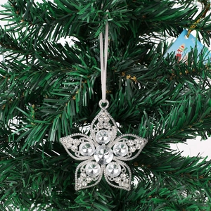 Close-up of sparkling silver star Christmas ornament with rhinestones on a green tree branch
