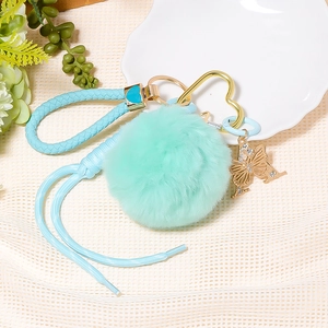 Detailed view of mint green plush ball keychain with blue heart clip and butterfly charm