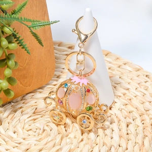 Detaillierte Makroansicht eines goldenen Kürbis-Schlüsselanhängers mit bunten Strasssteinen und Emaille