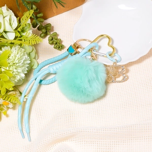 Detailed mint green pompom keychain featuring a golden heart ring and sparkling B pendant