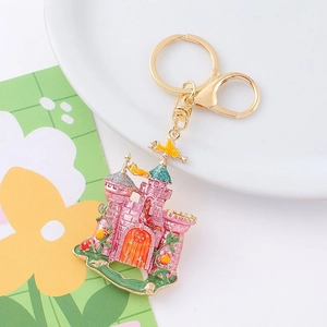 Detail of pink enamel fairy castle keychain with gold-plated ring on a white plate