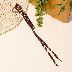 Detail of a dark brown braided paracord lanyard with a circular loop on rustic background